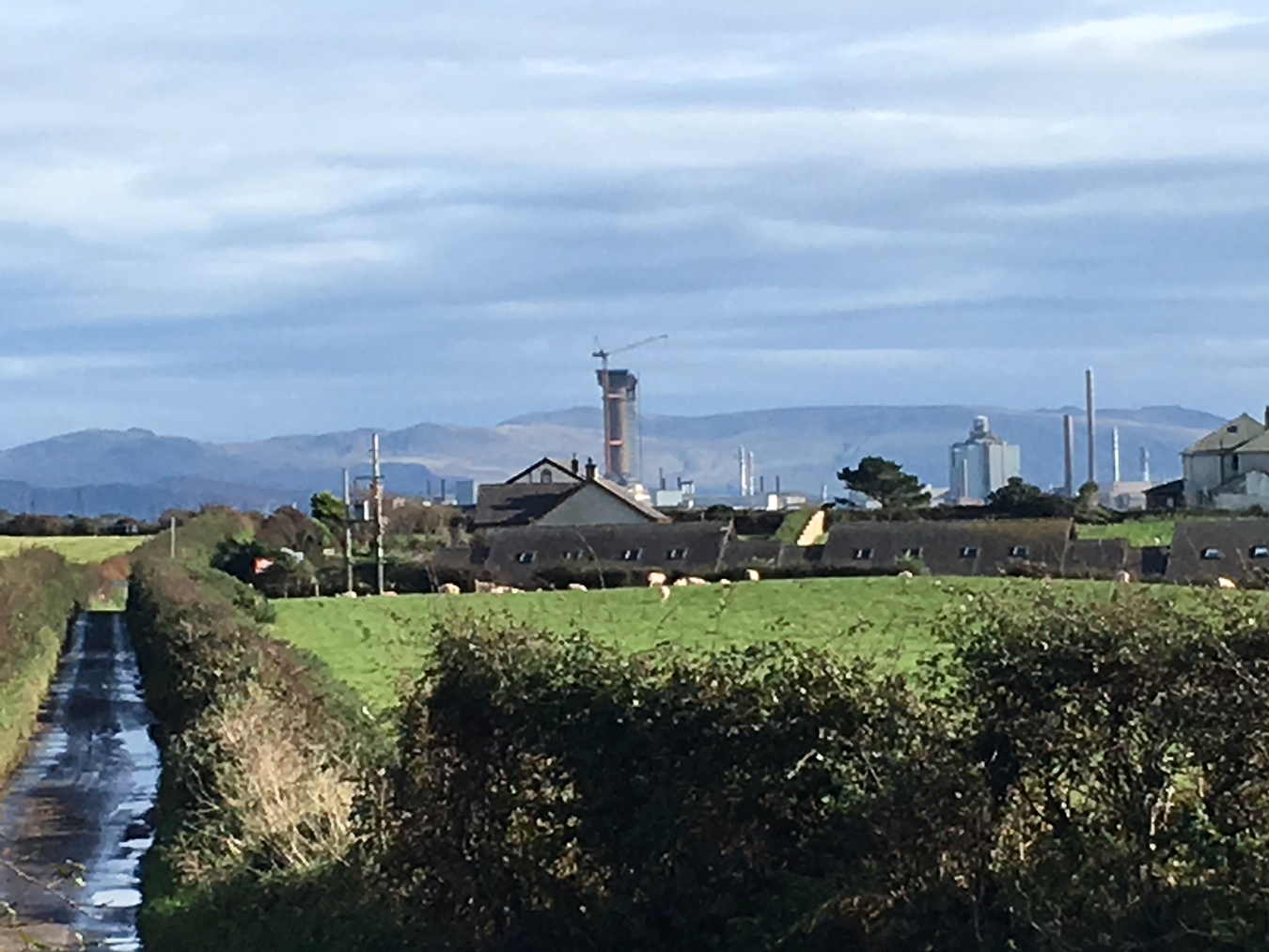 Sellafield site in its agricultural West Cumbrian habitat, with a farm in the foreground and Lake District fells in the background, just after the rain, 2019. Photo by Petra Tjitske Kalshoven.