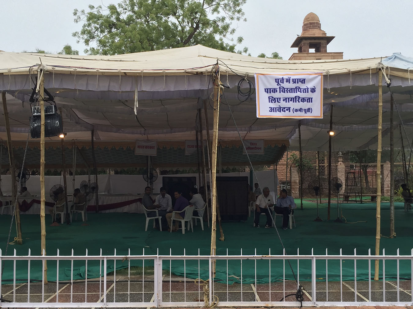 Sign for “Pending Pakistani Displaced People’s Citizenship Applications” hanging from tent top. Photo by Natasha Raheja.