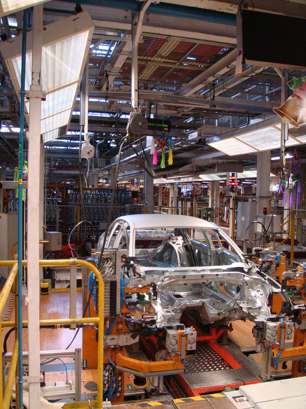 View of a car body during the Day of the Virgin of Guadalupe when the factory opens its doors to workers’ families. The celebration of the Virgin is a few days before Christmas, which is why there are piñatas in the background. Photo by Alejandra González Jiménez.