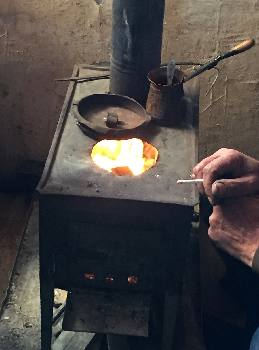 The Chemist smokes a cigarette as we sit together in front of a wood-burning stove and share a meal. Photo by Lori Khatchadourian.