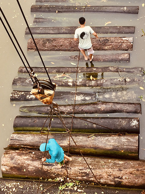 Workers walk on log rafts to secure the crane. Photo by Eduardo Romero Dianderas.