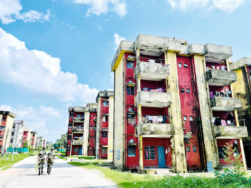 Two soldiers walk by a residential housing structure.