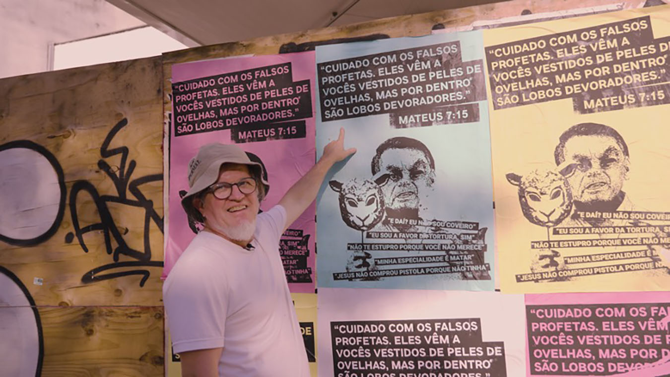 Brazilian artivist Julio Djocsar pointing at a poster bomb against Bolsonaro. Photo by Mihai Andrei Leaha).
