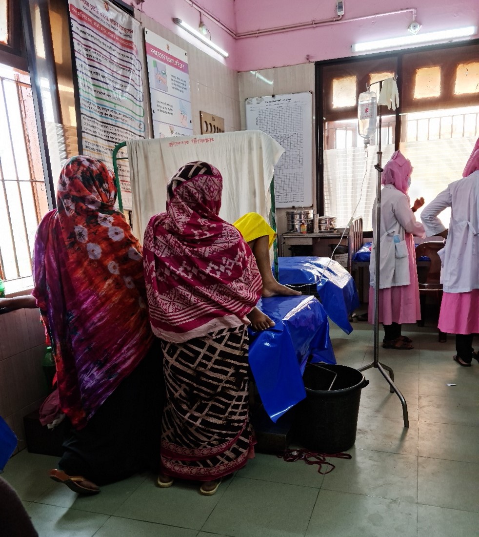 In this photo, a laboring woman’s attendants (rurgir-lok) stand next to her while midwife interns work on the other side of the room.