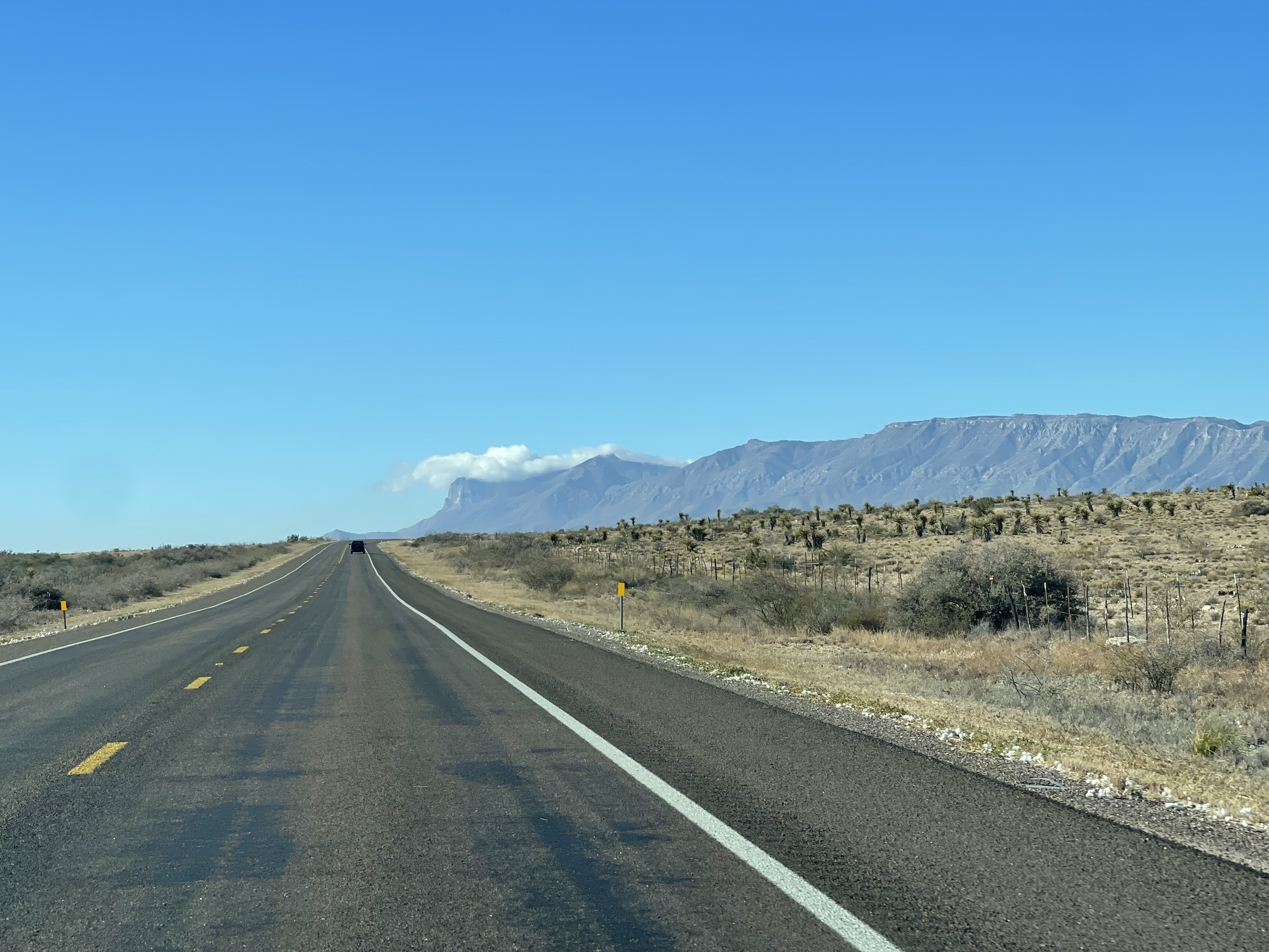 A desert highway runs parallel to distant mountains.