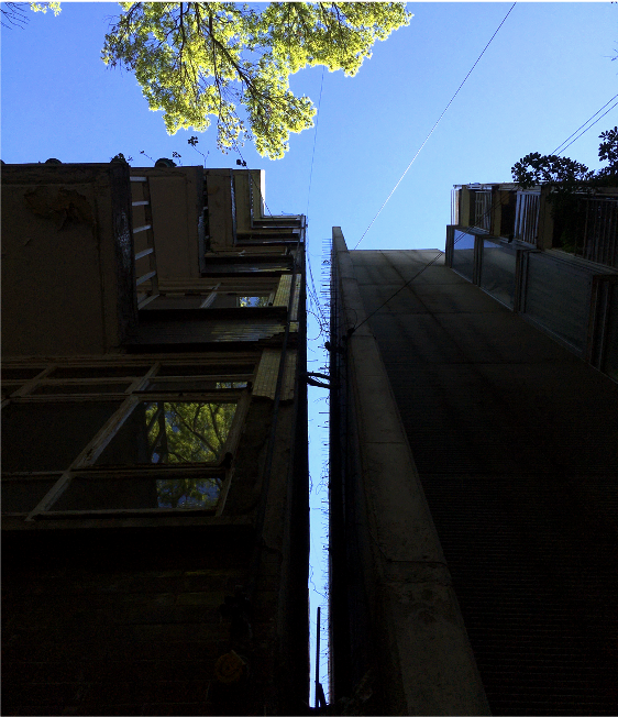 Photo taken from the base of two buildings that are splaying away from one another. The gap between the two buildings grows toward the top.