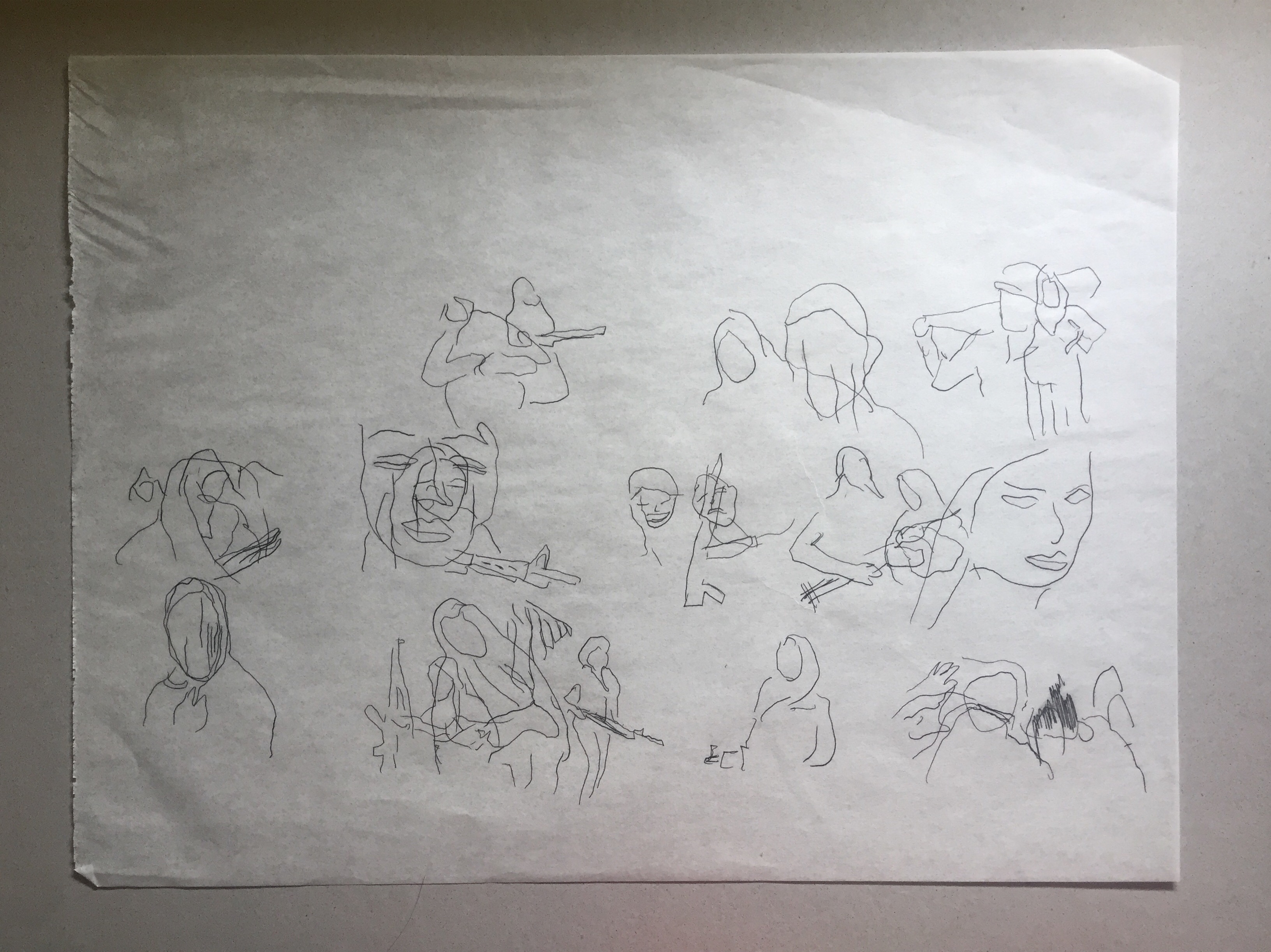 Drawing of women’s faces traced onto a large white canvas. Some of the drawings overlap merge and blur together.